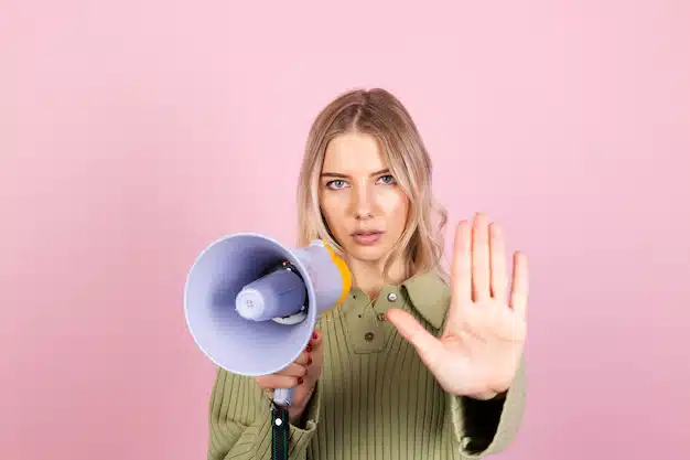 mulher segurando autofalante enquanto faz sinal de parar com a mão em uma postagem sobre comunicação não violenta